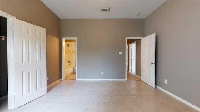 unfurnished bedroom with connected bathroom and light tile patterned flooring