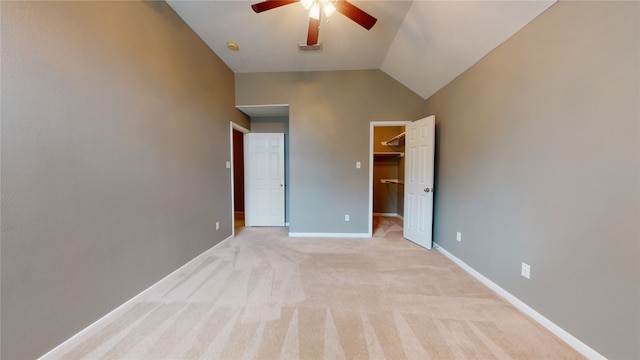 unfurnished bedroom with light carpet, vaulted ceiling, ceiling fan, a spacious closet, and a closet