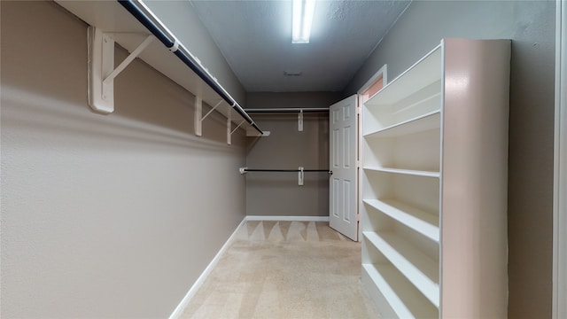 walk in closet featuring light carpet