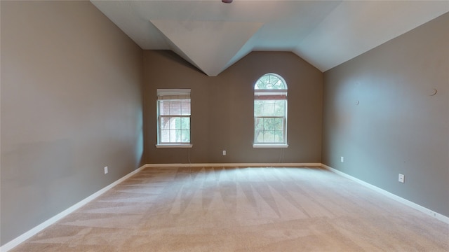 carpeted empty room featuring vaulted ceiling