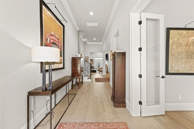 hallway featuring light wood-type flooring and ornamental molding