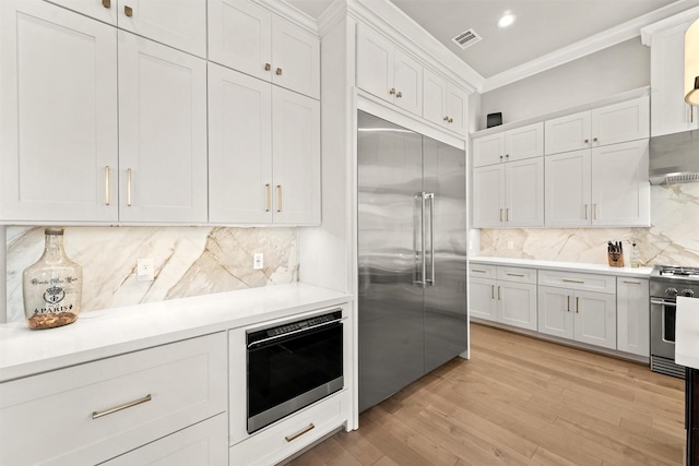 kitchen with backsplash, white cabinets, and appliances with stainless steel finishes