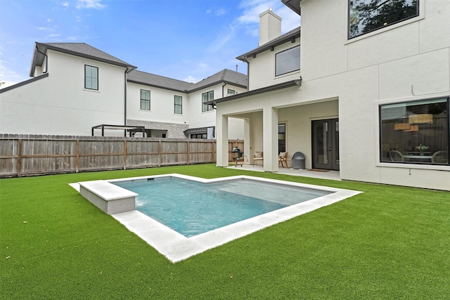 rear view of property featuring a patio, a fenced in pool, and a lawn