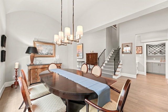 dining room featuring a chandelier, light hardwood / wood-style floors, and vaulted ceiling