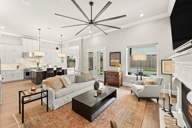 living room with french doors, light hardwood / wood-style floors, crown molding, and sink