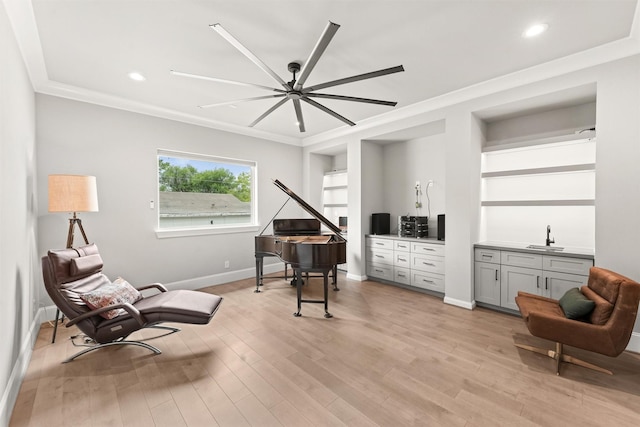 sitting room featuring light wood-type flooring, ceiling fan, crown molding, sink, and built in features