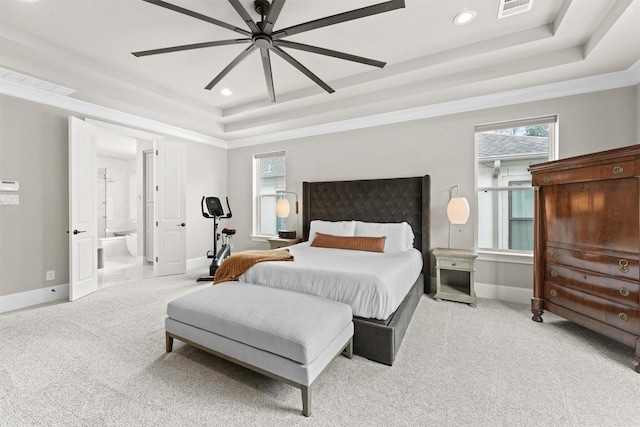 bedroom with a raised ceiling, ceiling fan, ensuite bathroom, and light carpet