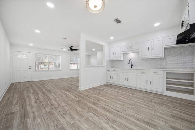 kitchen with white cabinetry, sink, ceiling fan, tasteful backsplash, and light hardwood / wood-style floors