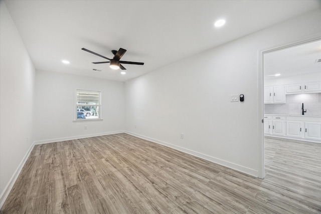 unfurnished room with ceiling fan, sink, and light wood-type flooring