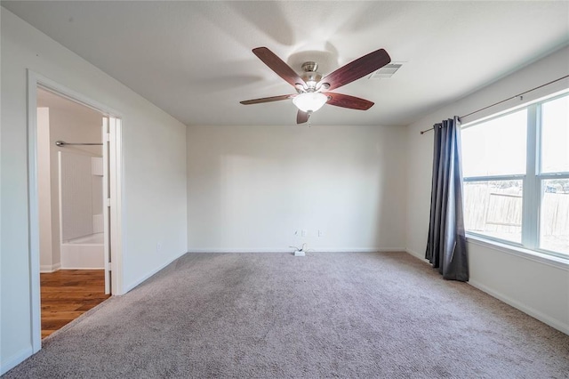 carpeted spare room featuring ceiling fan and plenty of natural light