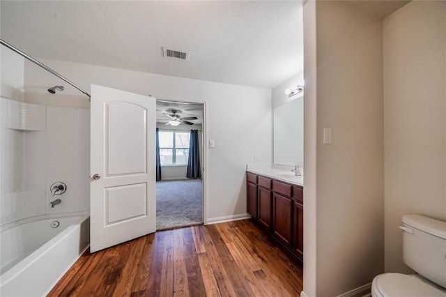 full bathroom with vanity, shower / washtub combination, ceiling fan, wood-type flooring, and toilet