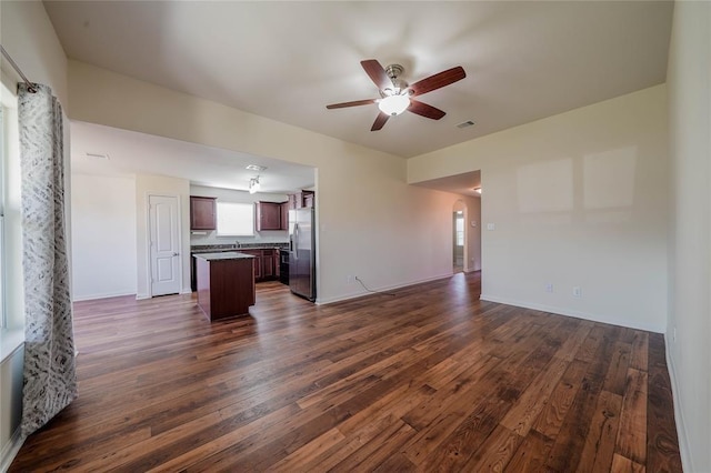 unfurnished living room featuring ceiling fan and dark wood-type flooring