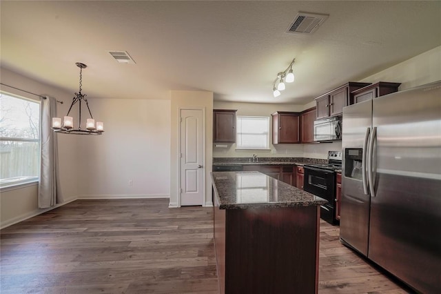 kitchen featuring stainless steel appliances, dark wood-type flooring, pendant lighting, a notable chandelier, and a kitchen island