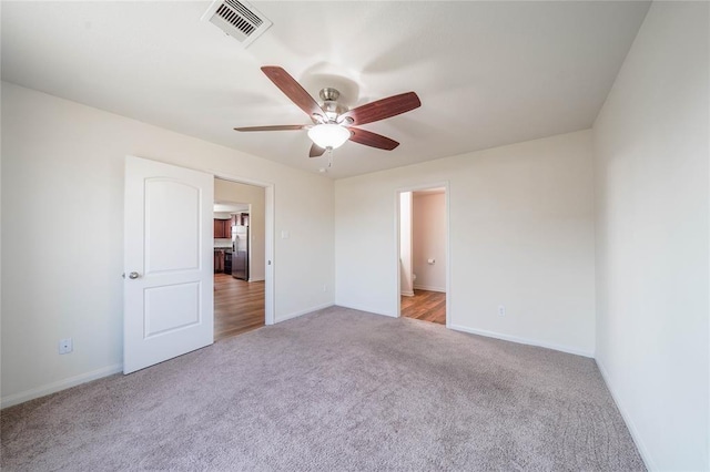 unfurnished bedroom with light carpet, stainless steel fridge, and ceiling fan