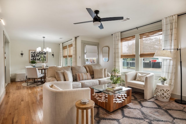 living room featuring ceiling fan with notable chandelier and light hardwood / wood-style floors