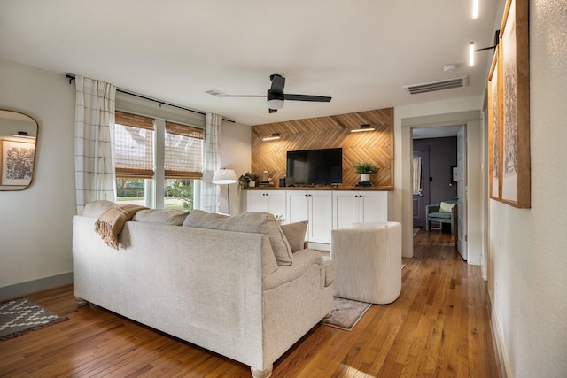 living room featuring hardwood / wood-style floors, ceiling fan, and wooden walls