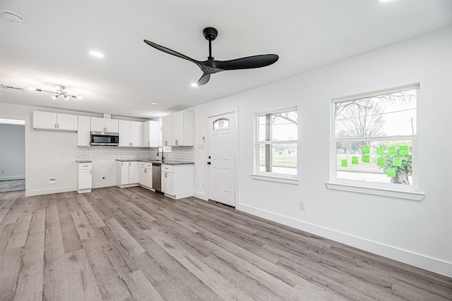 kitchen featuring white cabinetry, stainless steel appliances, tasteful backsplash, sink, and light wood-type flooring