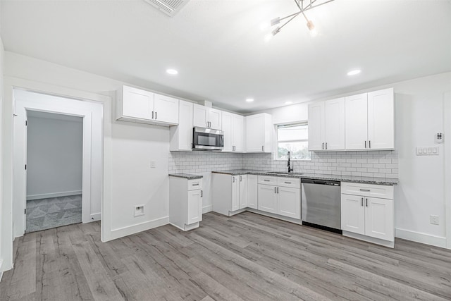 kitchen featuring white cabinets, appliances with stainless steel finishes, sink, and light wood-type flooring