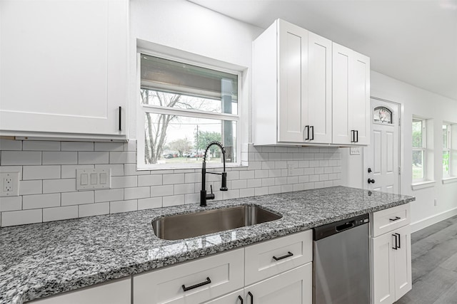 kitchen with white cabinetry, stainless steel dishwasher, light stone counters, and sink