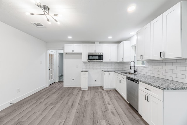 kitchen featuring light stone countertops, stainless steel appliances, white cabinets, and sink