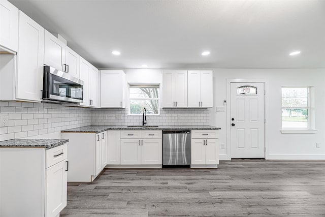 kitchen with light hardwood / wood-style floors, stainless steel appliances, plenty of natural light, white cabinets, and sink