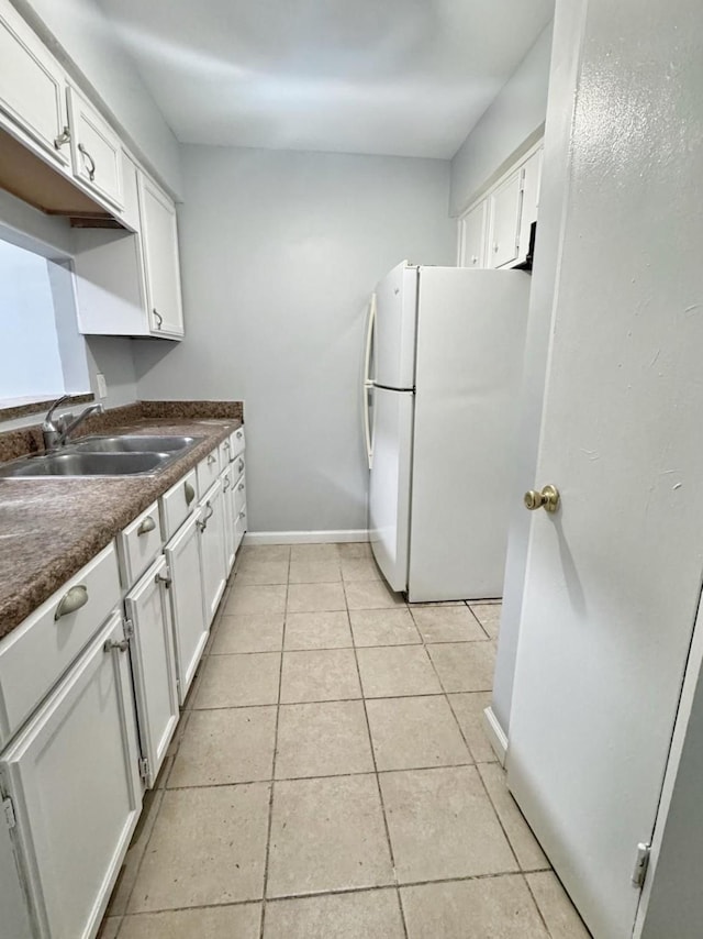 kitchen featuring white cabinets, sink, white fridge, and light tile patterned floors