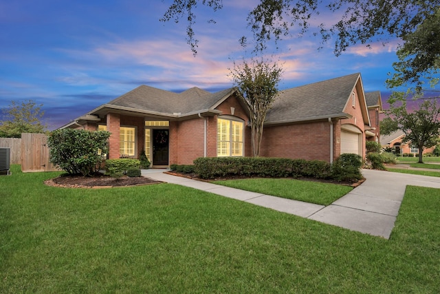 view of front of house with a yard, central AC, and a garage