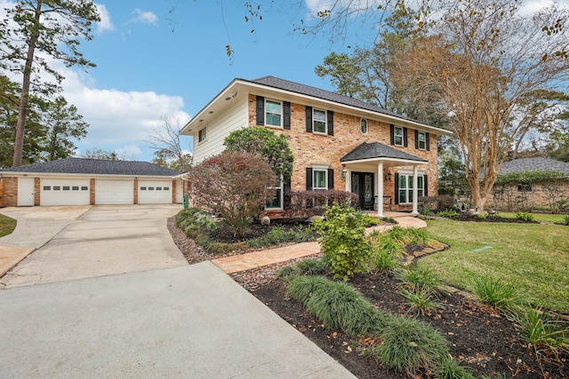 colonial-style house with brick siding, a detached garage, a front lawn, an outbuilding, and driveway