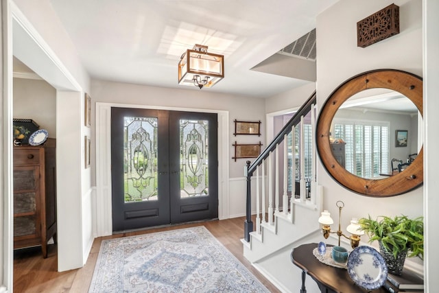 entrance foyer with a chandelier, plenty of natural light, french doors, and stairs