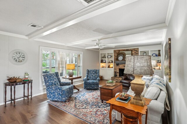 living room with a brick fireplace, dark hardwood / wood-style floors, ornamental molding, a textured ceiling, and built in shelves