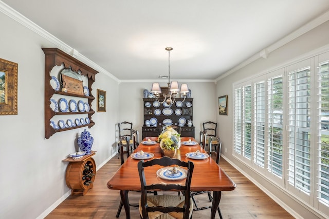 dining space with hardwood / wood-style flooring, ornamental molding, and an inviting chandelier