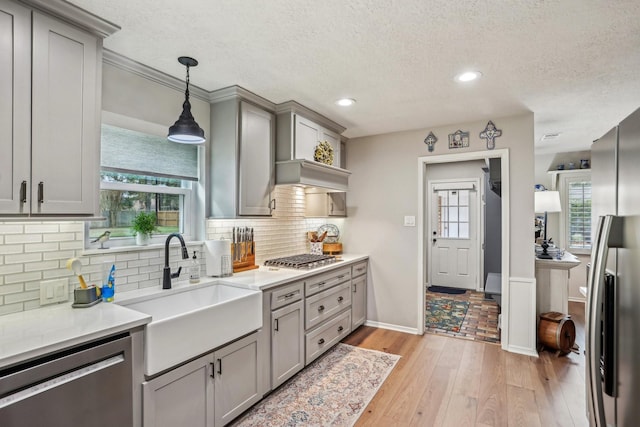 kitchen with gray cabinets, sink, light hardwood / wood-style flooring, hanging light fixtures, and stainless steel appliances