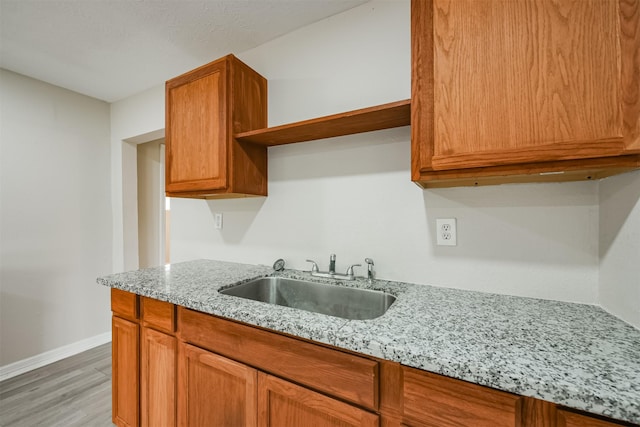 kitchen featuring light hardwood / wood-style floors, light stone countertops, and sink