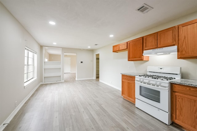 kitchen featuring white gas range, light stone countertops, and light hardwood / wood-style floors