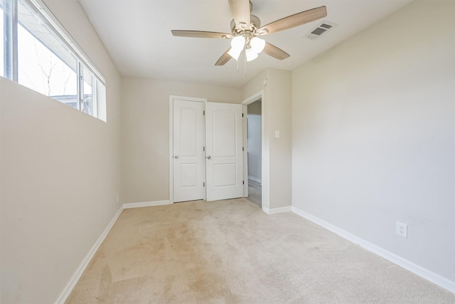 empty room with ceiling fan and light colored carpet