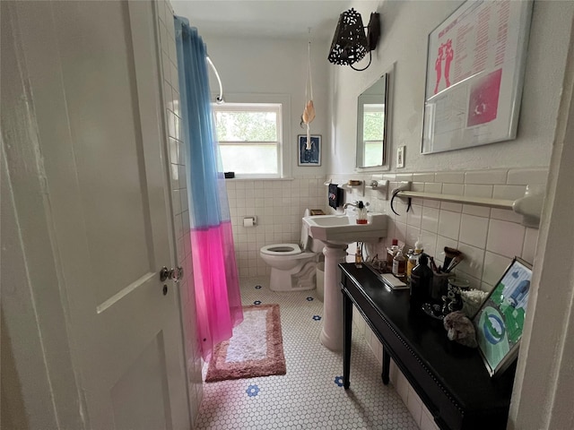 bathroom featuring sink, tile walls, and toilet