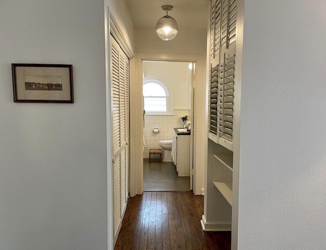 hall featuring dark wood-type flooring and tile walls