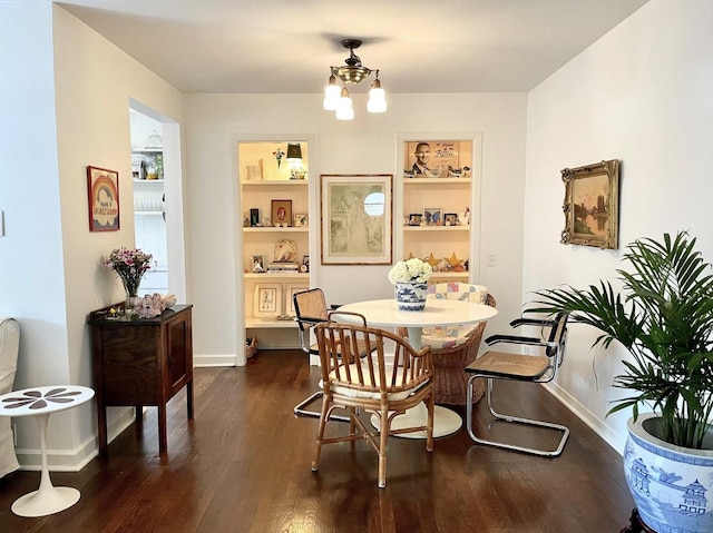 dining room with dark hardwood / wood-style floors, built in features, and an inviting chandelier