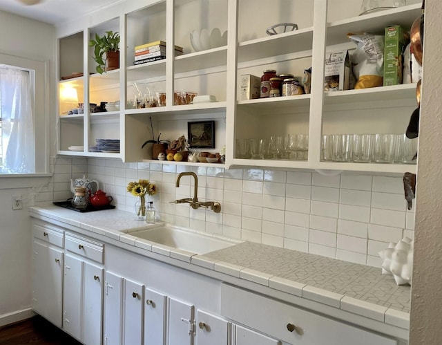 kitchen featuring white cabinets, decorative backsplash, sink, and tile counters