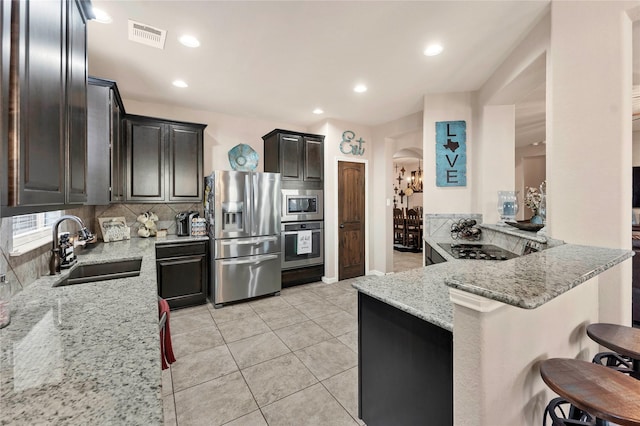 kitchen featuring light stone countertops, sink, a kitchen breakfast bar, kitchen peninsula, and appliances with stainless steel finishes