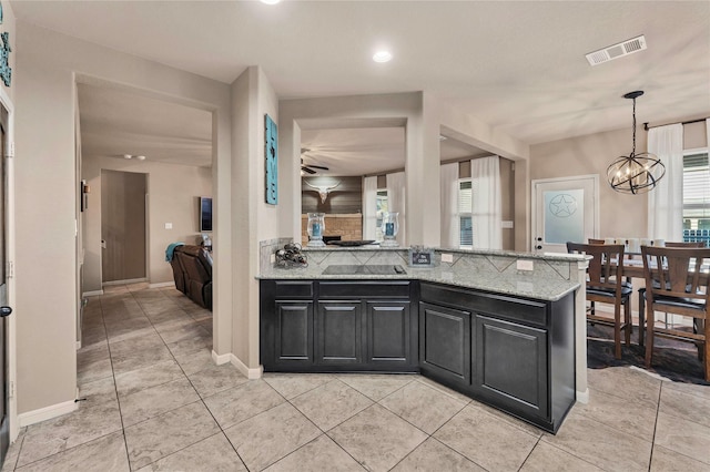 kitchen featuring ceiling fan with notable chandelier, light stone countertops, and a wealth of natural light