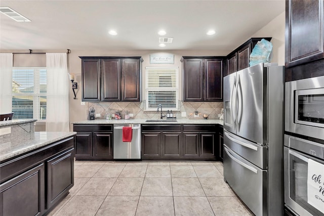 kitchen featuring sink, decorative backsplash, appliances with stainless steel finishes, dark brown cabinets, and light tile patterned flooring