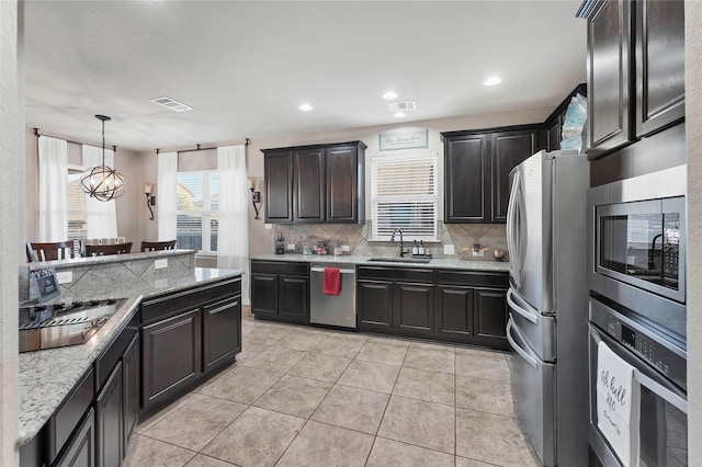 kitchen featuring stainless steel appliances, sink, pendant lighting, light tile patterned floors, and a notable chandelier