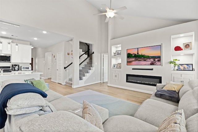 living room with high vaulted ceiling, ceiling fan, and light hardwood / wood-style floors