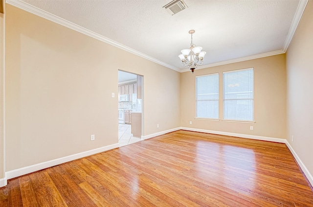 unfurnished room featuring a textured ceiling, light hardwood / wood-style floors, an inviting chandelier, and ornamental molding