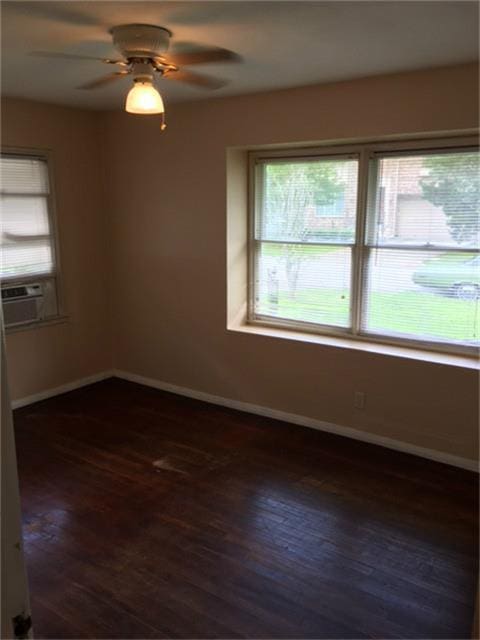 empty room featuring dark wood-type flooring, ceiling fan, and cooling unit