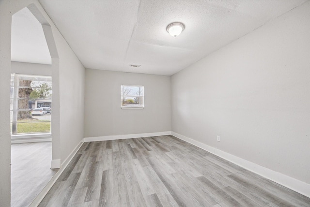 unfurnished room with a textured ceiling and light hardwood / wood-style flooring