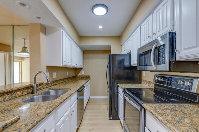 kitchen with white cabinets, sink, dark stone countertops, light hardwood / wood-style floors, and stainless steel appliances