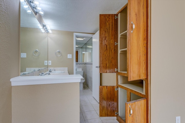 bathroom with tile patterned floors, vanity, toilet, and a textured ceiling