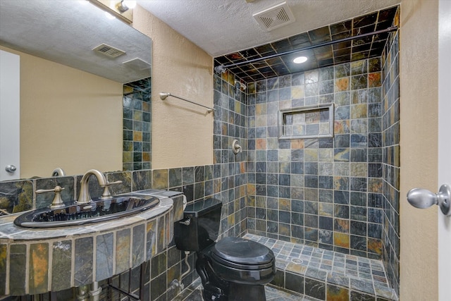 bathroom featuring tiled shower, sink, a textured ceiling, and toilet